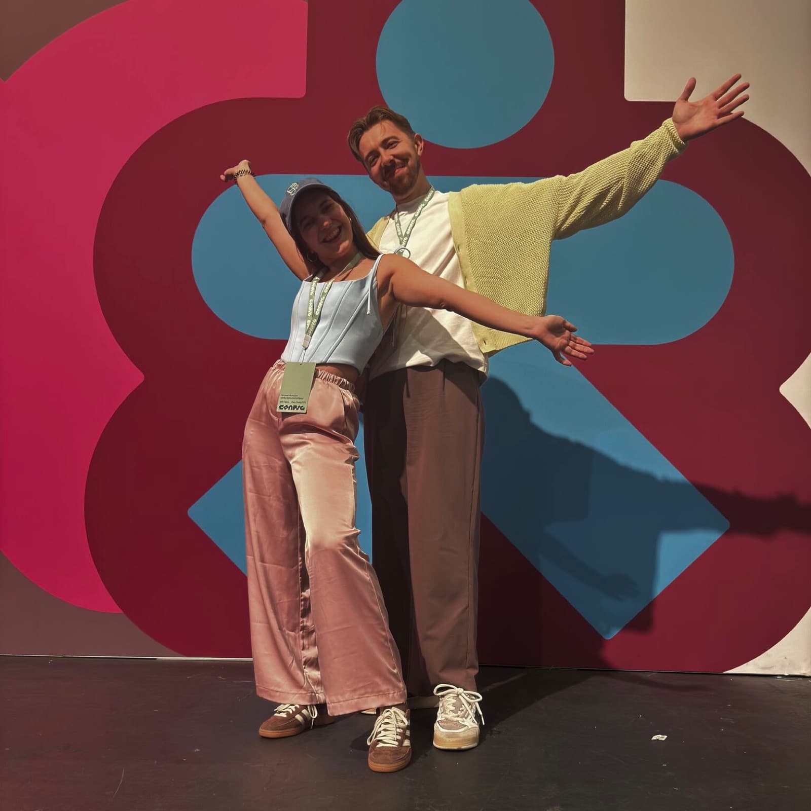 Tanya and me striking a pose with arms out in front of a huge pink and blue Config wall graphic