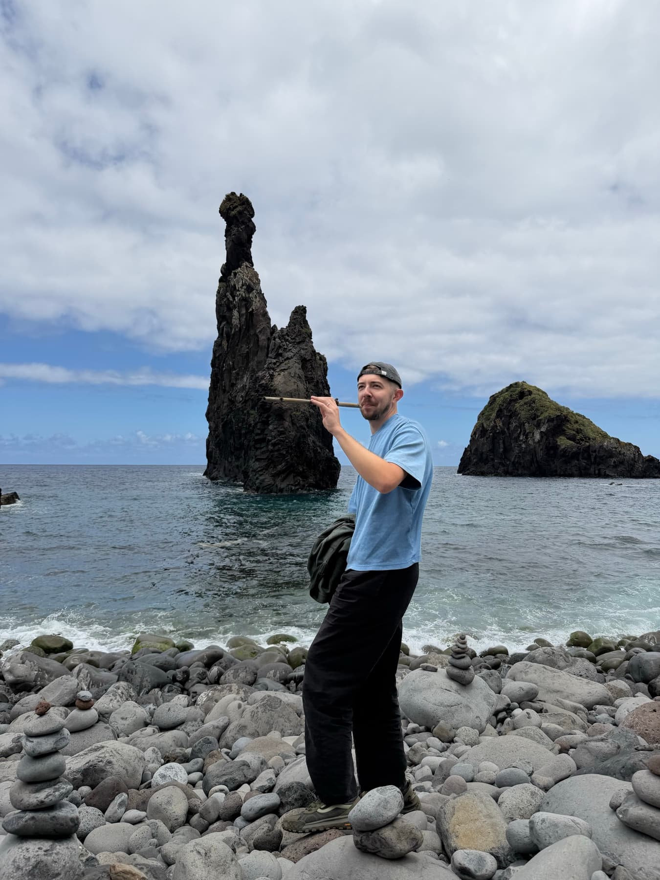 Standing on a pebble beach in front of a rock stack rising out of the sea