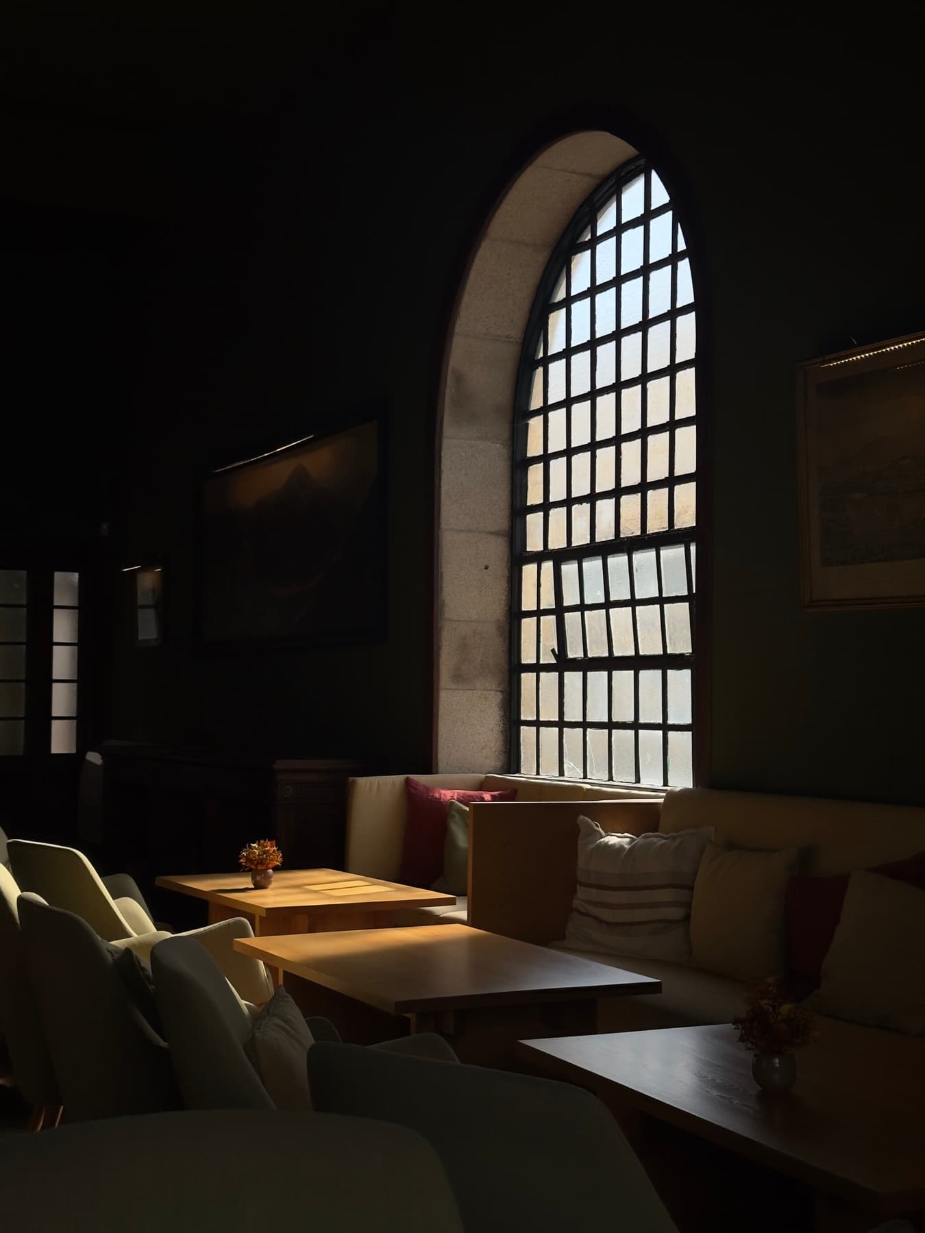 An arched window in a dim room, sunlight falling across the tables